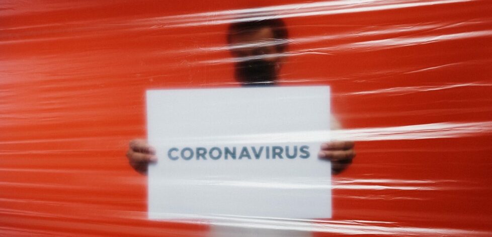 man-behind-a-plastic-holding-a-poster-of-coronavirus-3952185